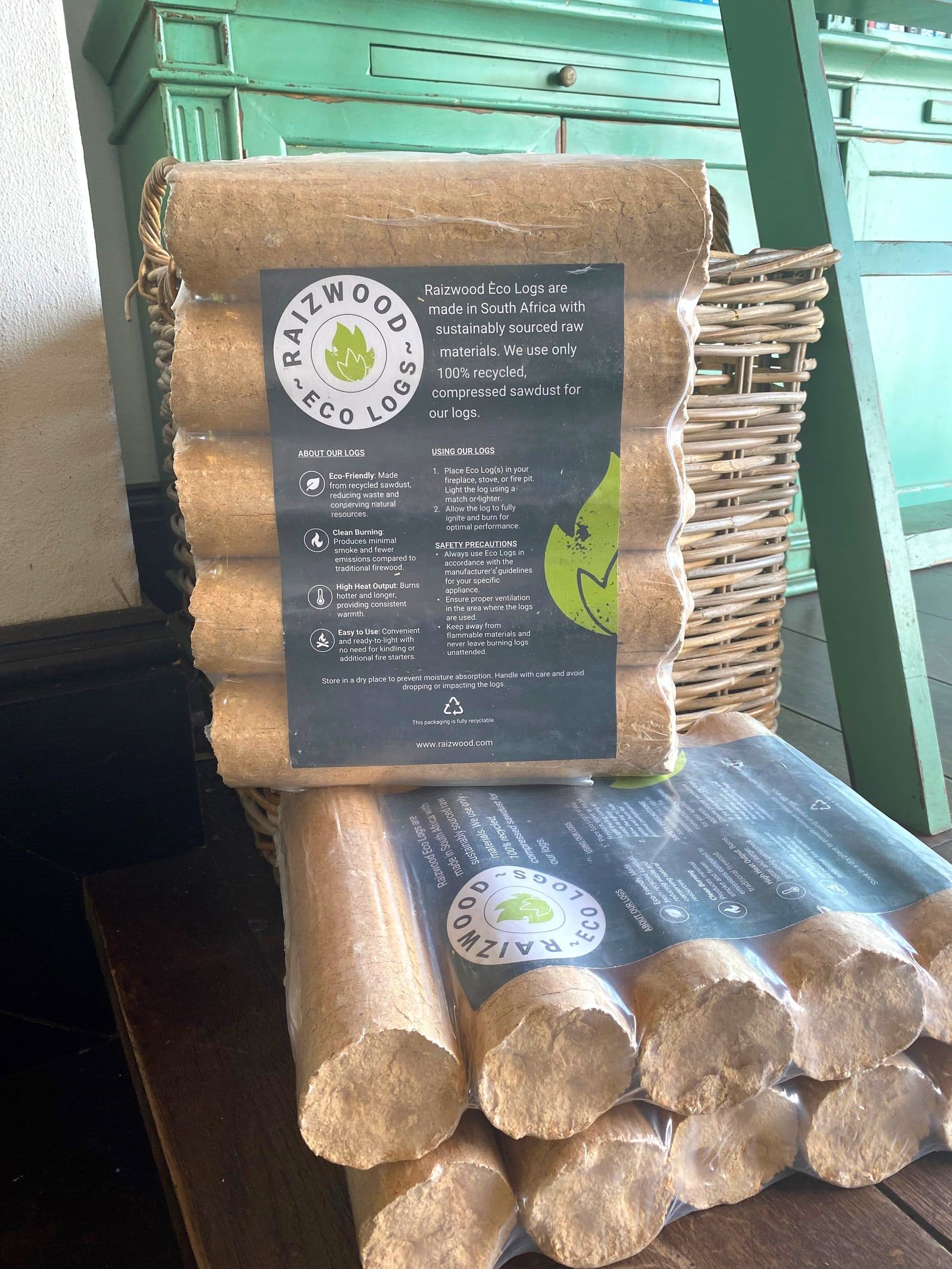 Packs of Raizwood Eco Logs stacked in front of a wicker basket